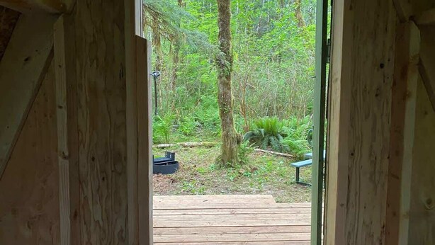 Puinen terassi, joka johtaa metsäiselle alueelle, jossa on penkki ja pieni pöytä.