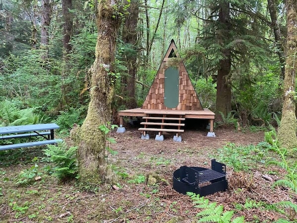 Una cabaña de madera con techo triangular en un bosque.