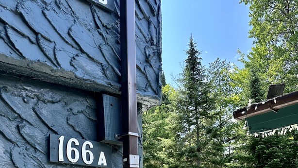 A wooden deck with outdoor furniture, a stone wall, and a sign reading "166A".
