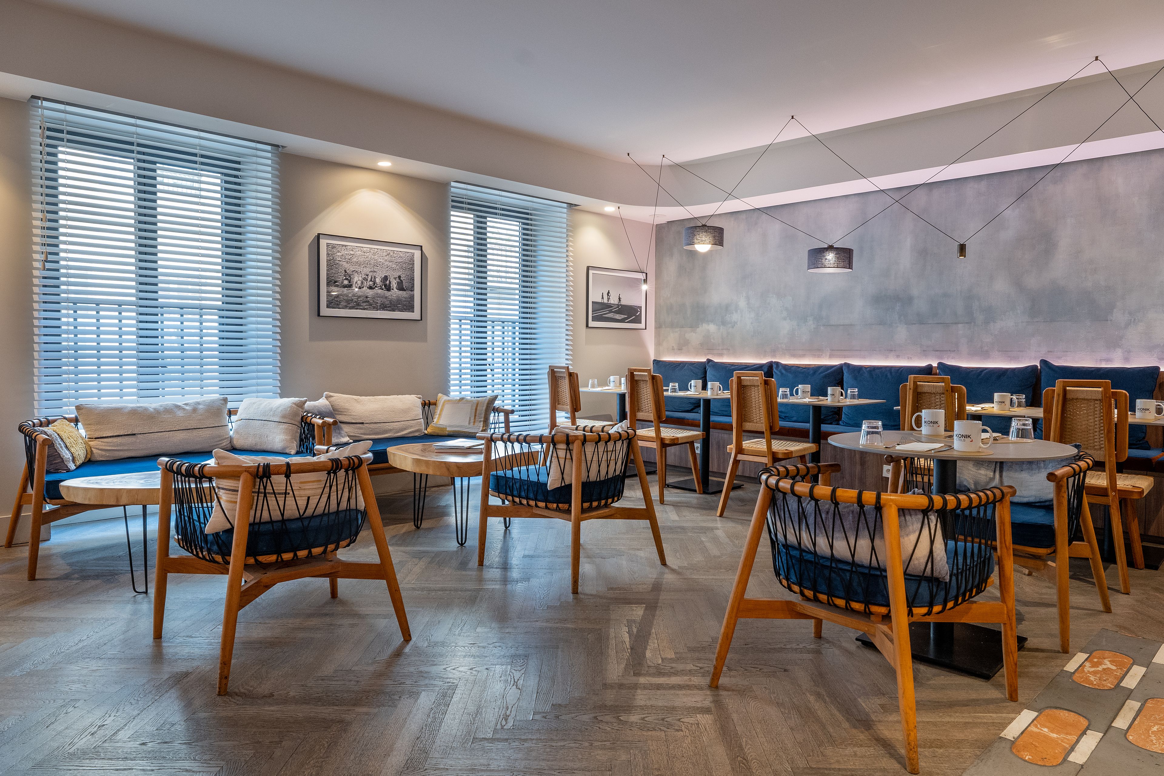 A modern dining area with wooden chairs and tables, a sofa, and artwork on the walls.