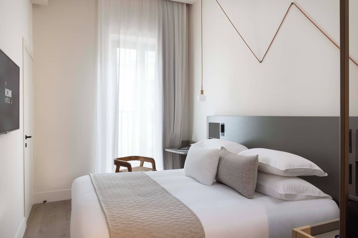 Ein modernes Hotelzimmer mit einem großen Bett, einem Schreibtisch und einem Fernseher.