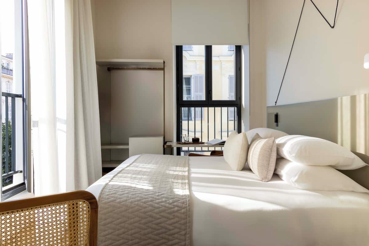 Ein Hotelzimmer mit Bett, Schreibtisch und Blick nach draußen.