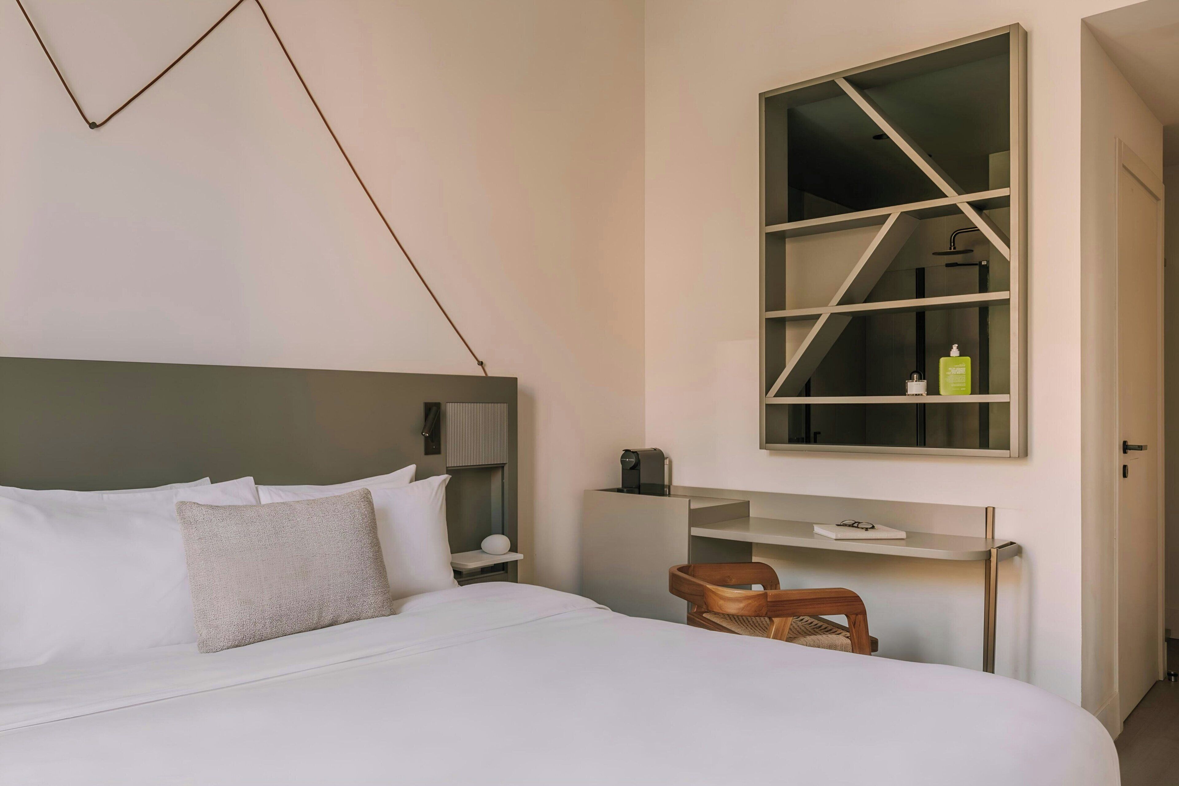 Una habitación de hotel moderna con una cama grande, un escritorio y un vestuario con ducha integrado.