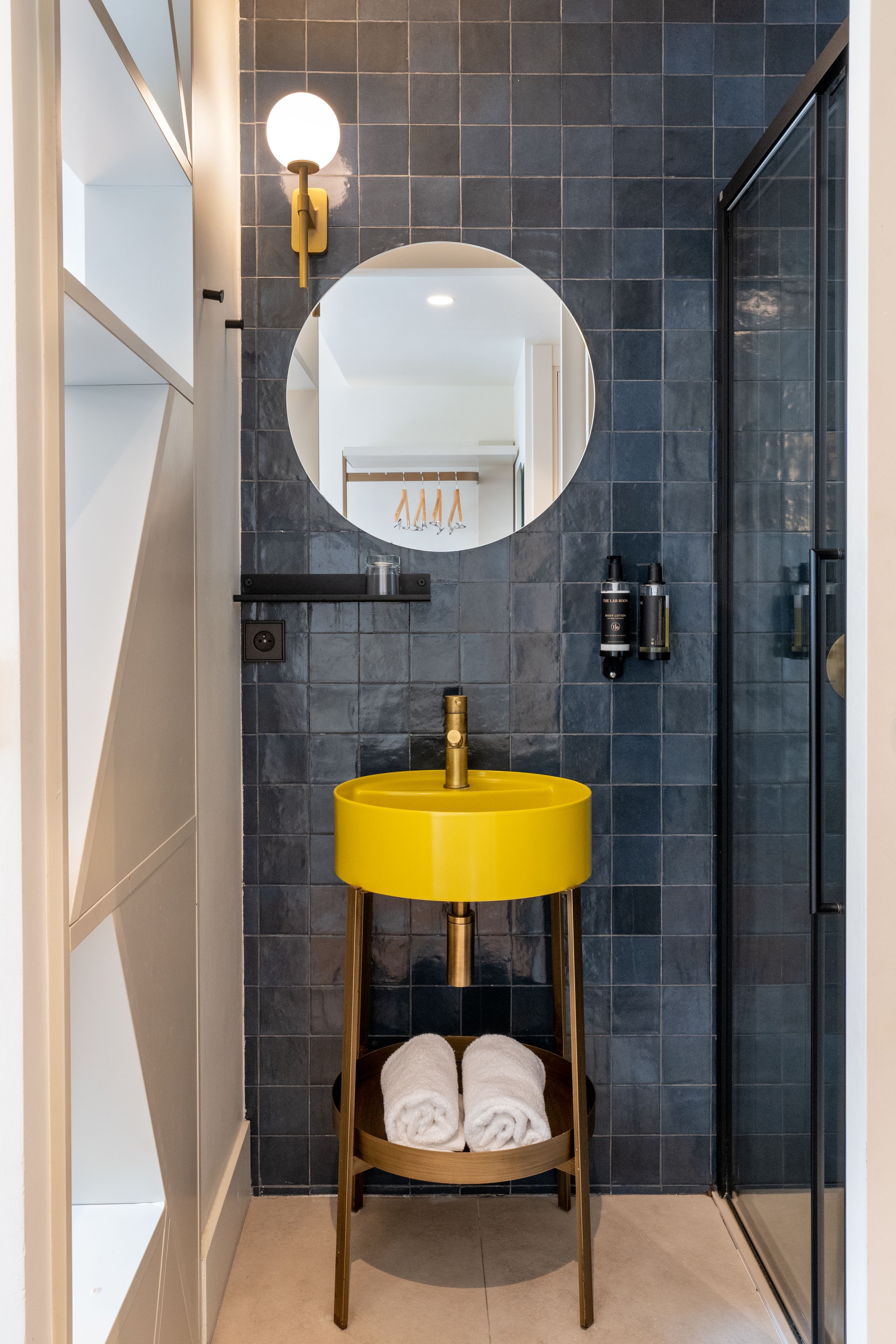 Une salle de bain avec un lavabo jaune, un miroir et un porte-serviettes.