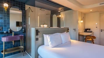 Une chambre d’hôtel moderne avec un grand lit, une salle de bain avec douche et un meuble-lavabo avec un évier.