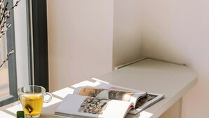 Una mesa en esquina con una revista, una taza de té y una silla de mimbre.