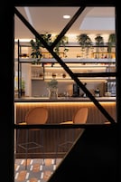 Uma cozinha moderna com área de bar, incluindo máquina de café, prateleiras com copos e plantas penduradas.