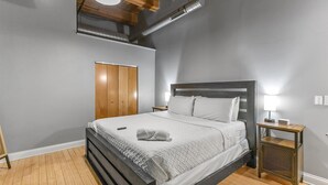 Een slaapkamer met een bed, een nachtkastje, een houten kledingkast en een ventilatie rooster.