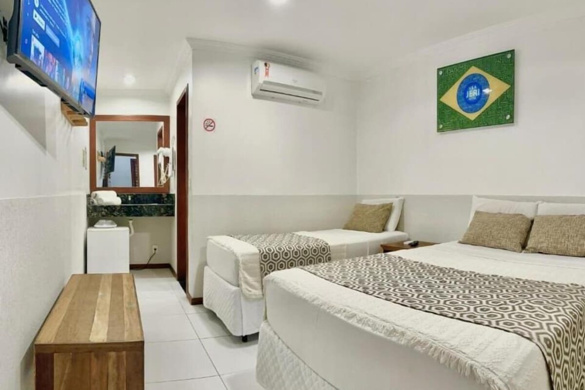 Habitación de hotel con dos camas, un televisor, una mesita y una decoración con la bandera de Brasil.