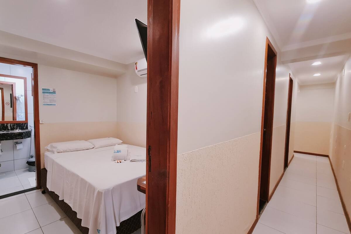 Een hotelkamer met een bed, een klein tafeltje en een badkamer zichtbaar door een geopende deur.