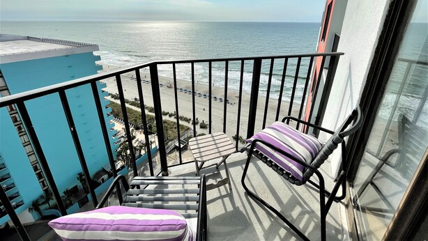 A balcony with a view of the beach and ocean.
