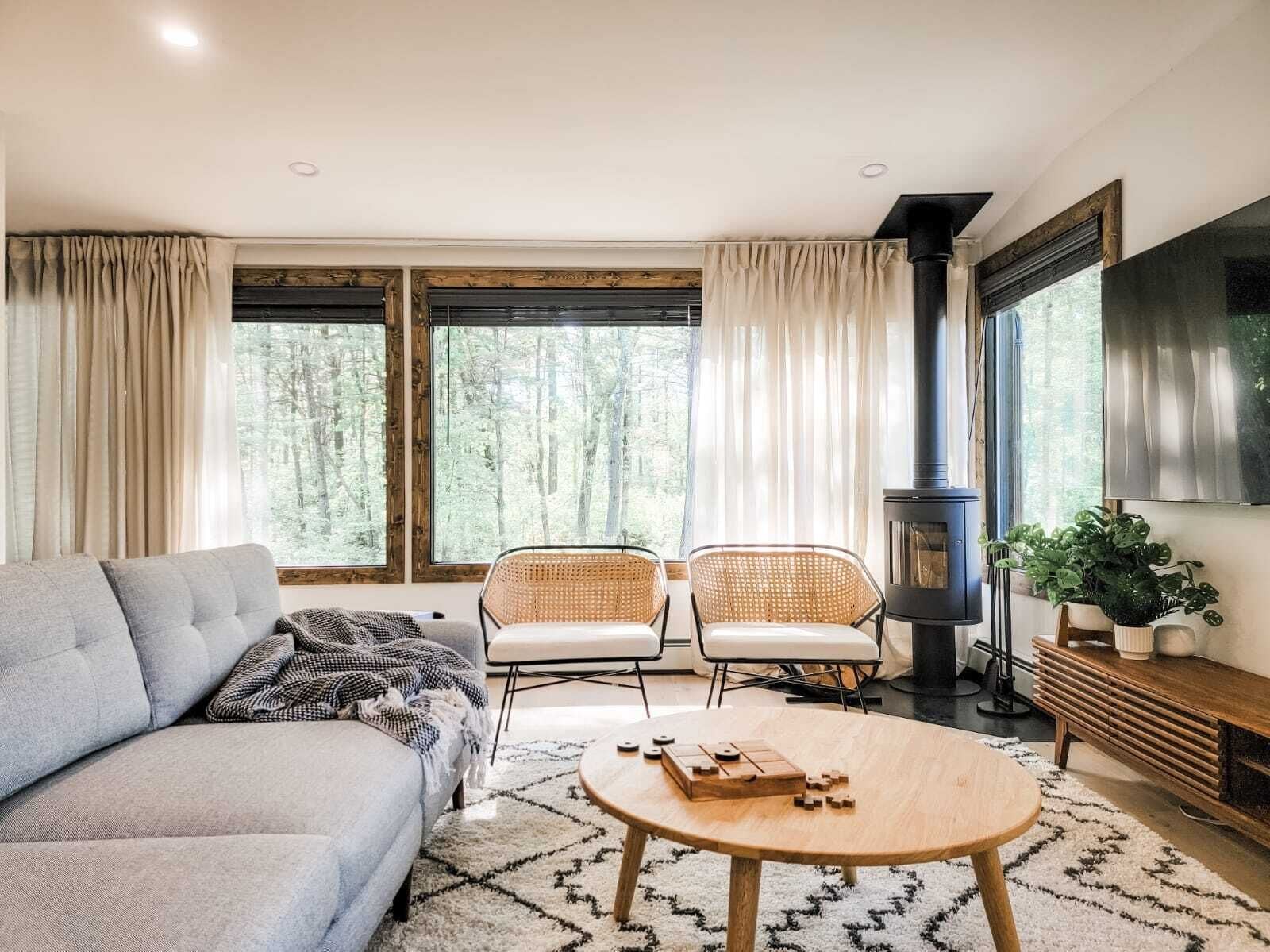 Un salon confortable avec un canapé, deux fauteuils, une table basse, un téléviseur et une cheminée.
