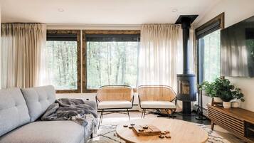 Un salon confortable avec un canapé, deux fauteuils, une table basse, un téléviseur et une cheminée.