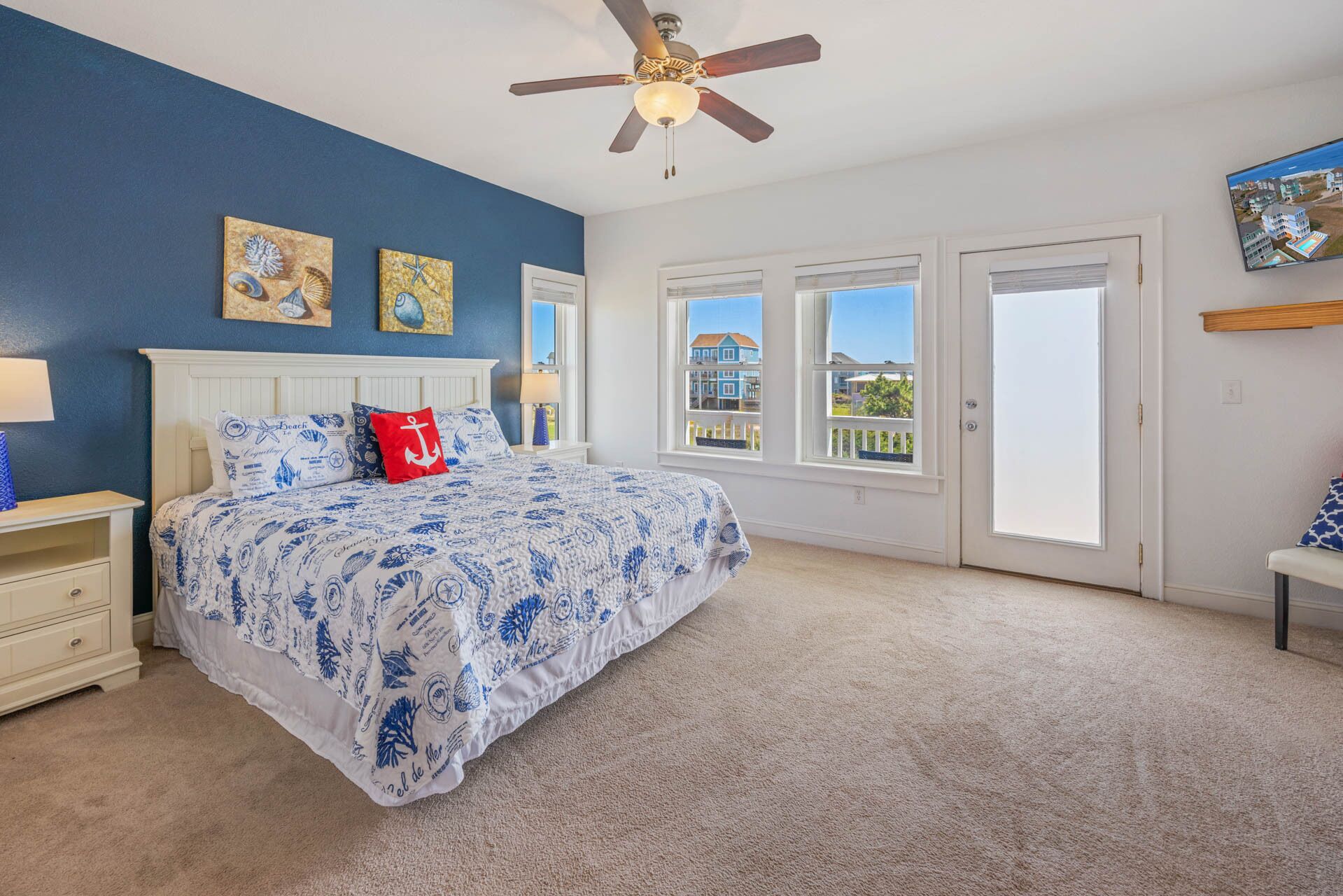 A bedroom with a bed, a nightstand, a ceiling fan, and a window with a view of buildings.