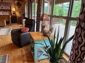 A cozy room with a wooden floor, a black leather chair, a turquoise table, and a large plant. - Couple's retreat! Studio cabin w/mountain views (Suches)