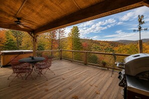 A covered outdoor deck with a wooden table and chairs, a barbecue grill, and a hot tub. - Couple's retreat! Studio cabin w/mountain views (Suches)