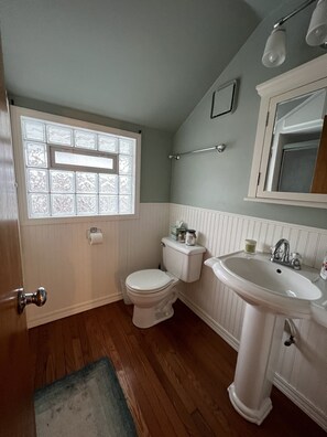 Une salle de bain comprenant des toilettes, un lavabo et une fenêtre ornée de panneaux de verre décoratifs.