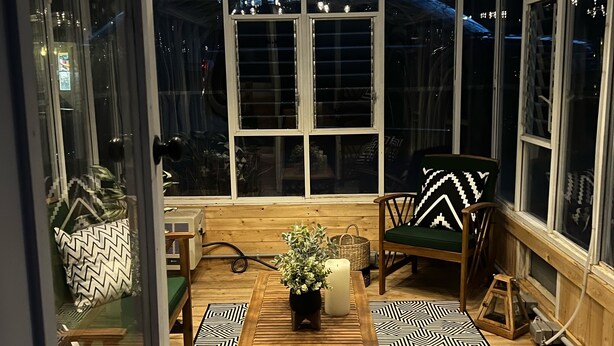 A conservatory with a wooden table, chairs, and a patterned floor.