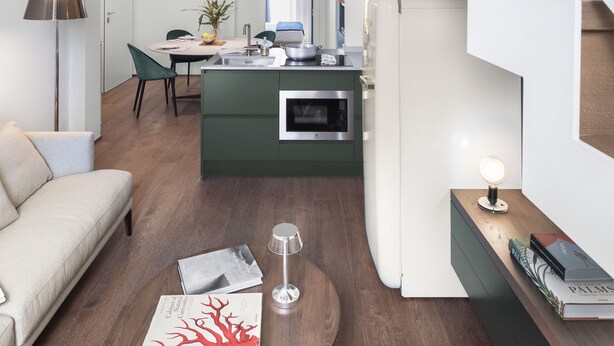 A modern living space with a staircase, a dining area, and a kitchen.
