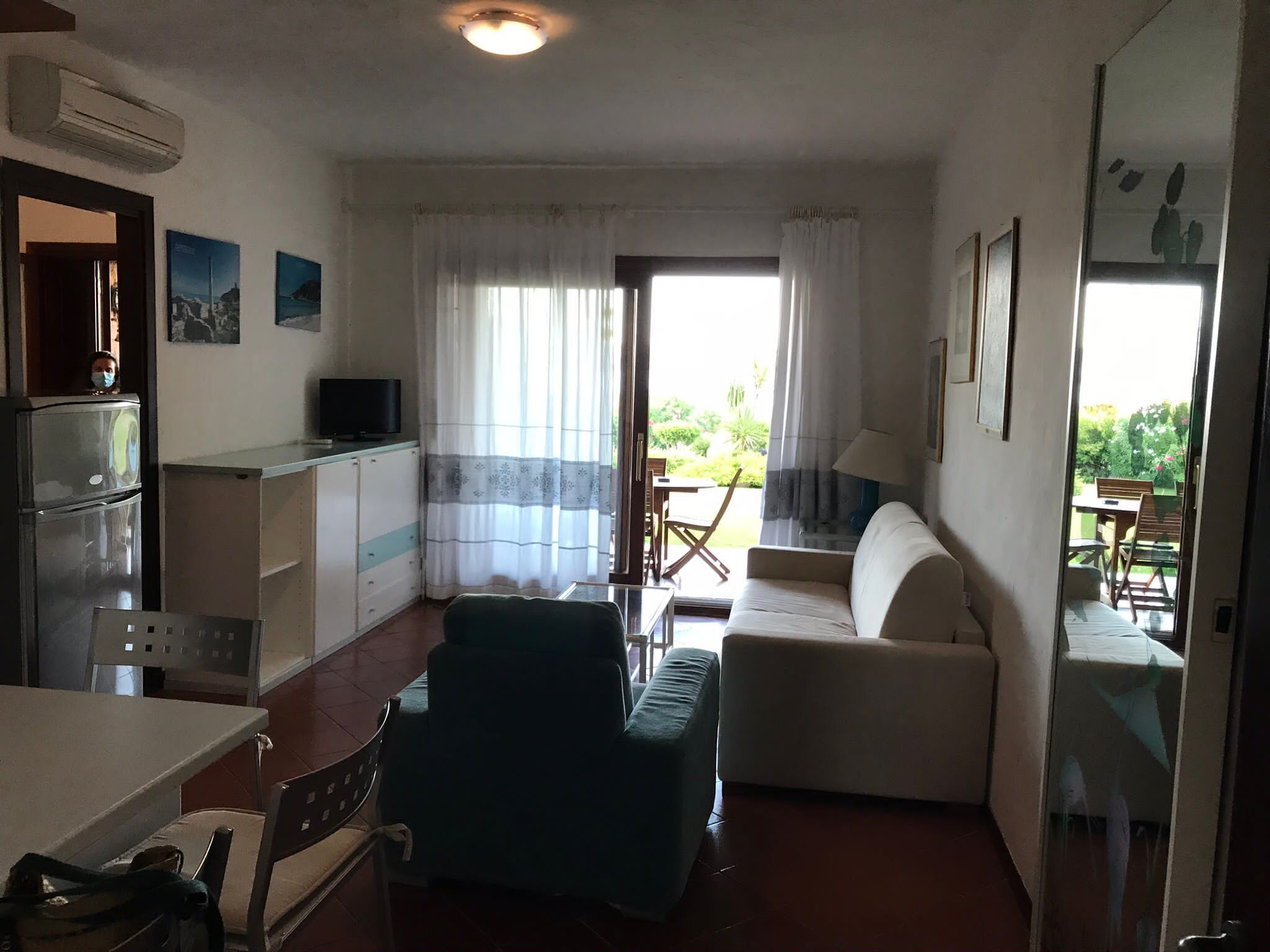 A compact living space with a kitchenette, a sofa, a dining table, and a view of the outdoors.