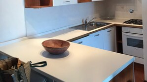 A modern kitchen with white cabinets, a wooden countertop, a gas stove, and a built-in oven. - Bilocale Vista Mare (San Teodoro)