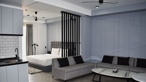 A modern living room with a sofa, coffee table, and a bed with a headboard. - Bedchambers Serviced Apartments, MG ROAD (Gurugram)