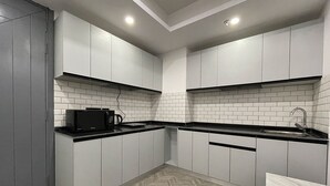 A modern kitchen with grey cabinets, white subway tiles, and a herringbone wood floor. - Bedchambers Serviced Apartments, MG ROAD (Gurugram)