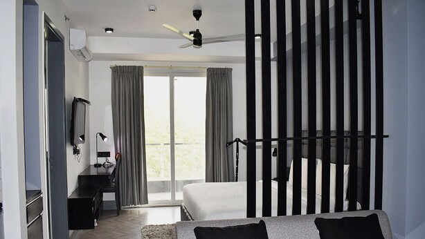 A modern bedroom with a bed, a desk, and a sofa. - Bedchambers Serviced Apartments, MG ROAD (Gurugram)