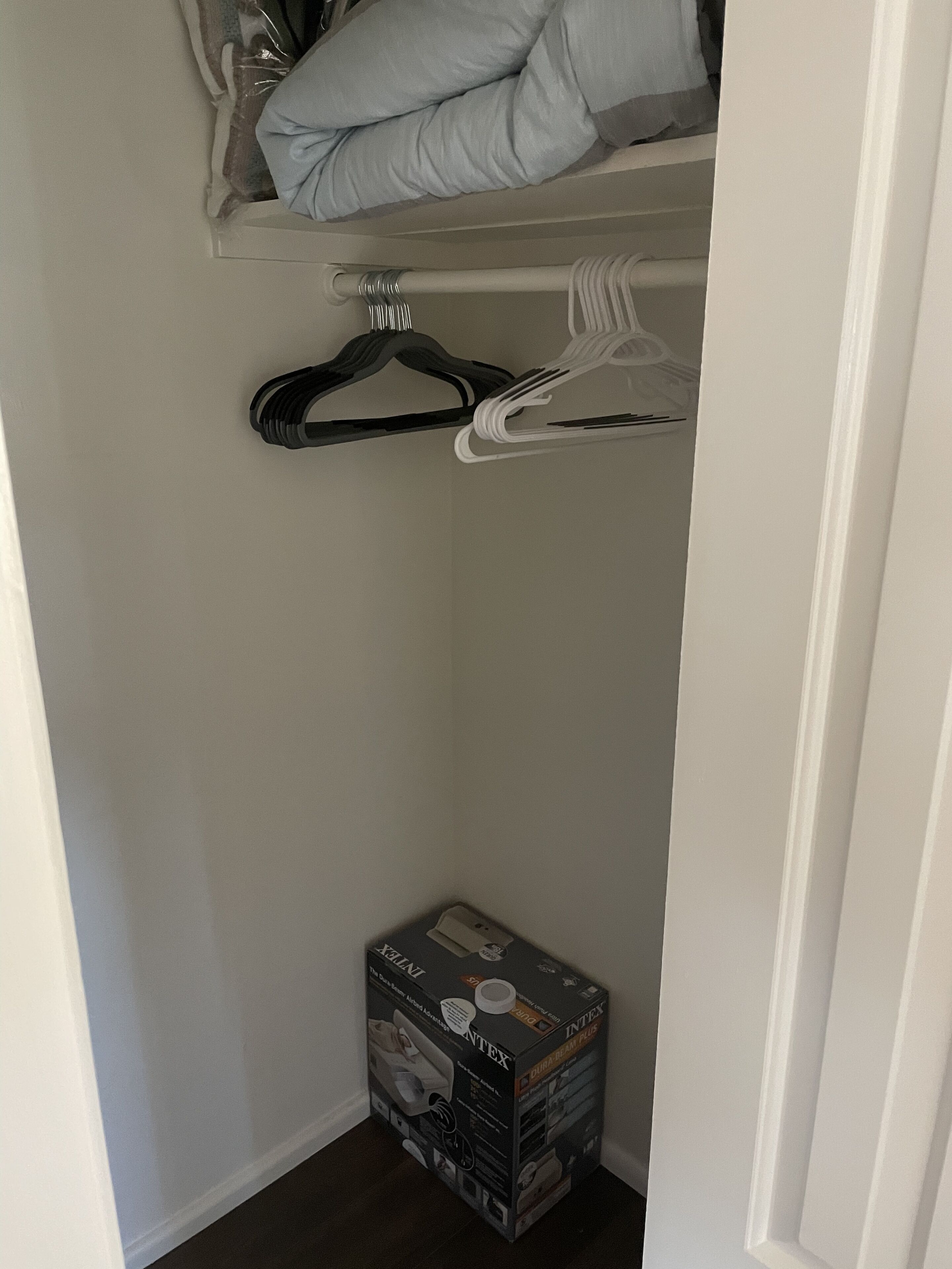 Ein Kleiderschrank mit einer hängenden Organizer-Tasche, einer Kiste mit Aufbewahrungsboxen und einem gefalteten Handtuch auf der obersten Ablage.
