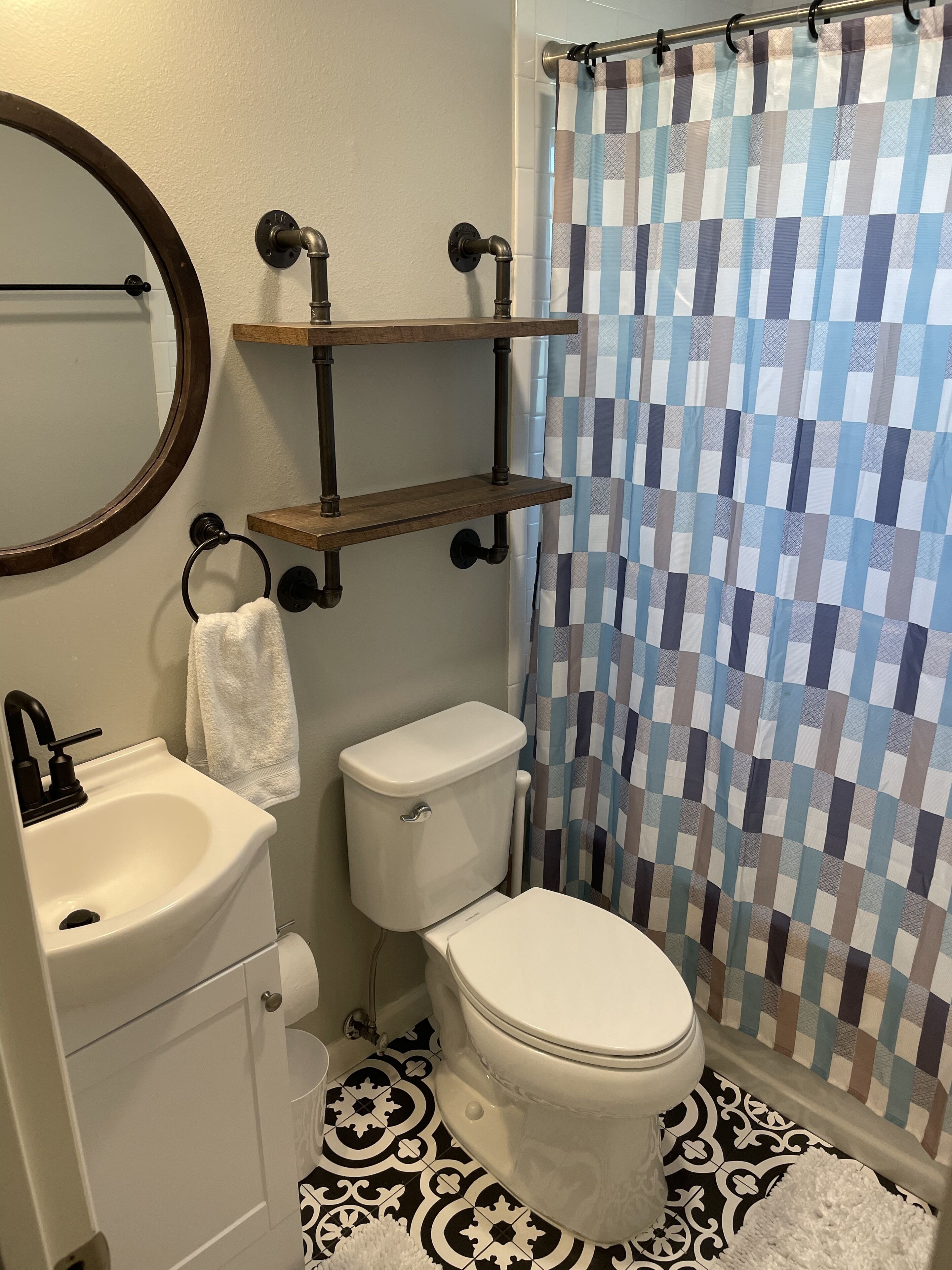 Un baño con inodoro, lavamanos y cortina de ducha a cuadros.