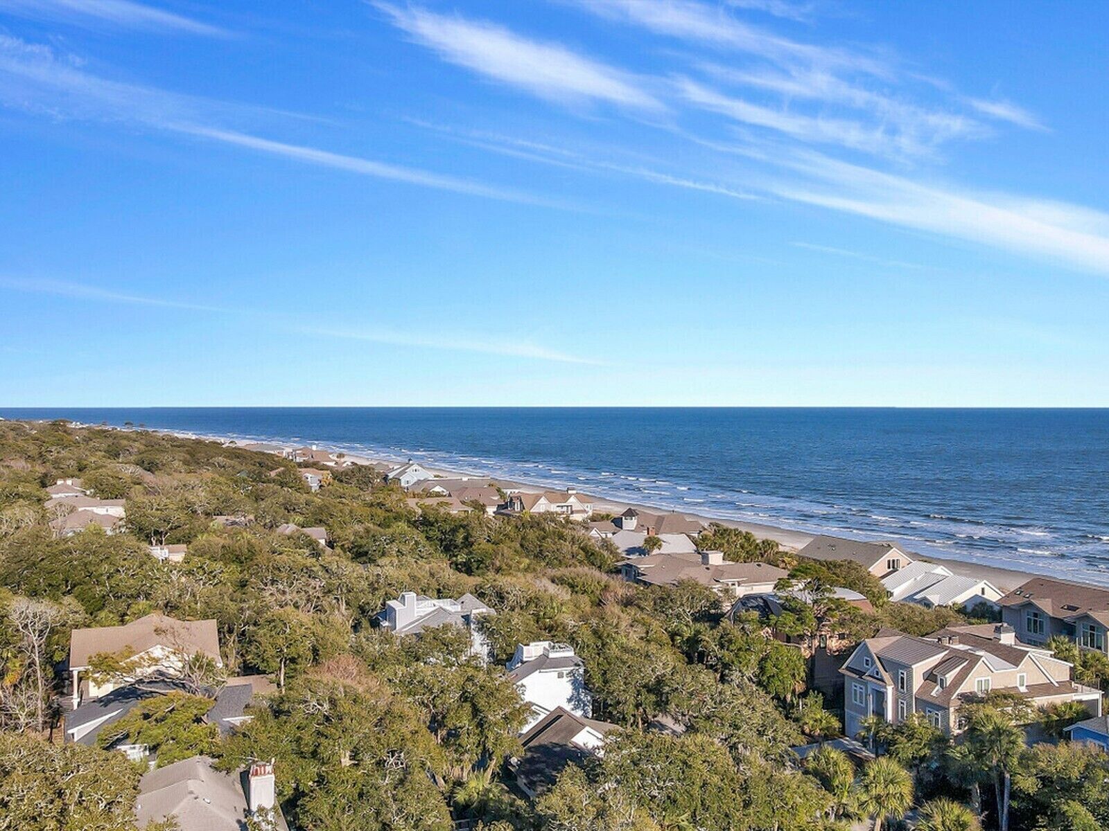 Un área residencial costera con casas rodeadas de árboles y vista al océano.