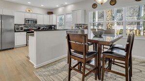 A modern kitchen with white cabinets, stainless steel appliances, and a central island with seating.