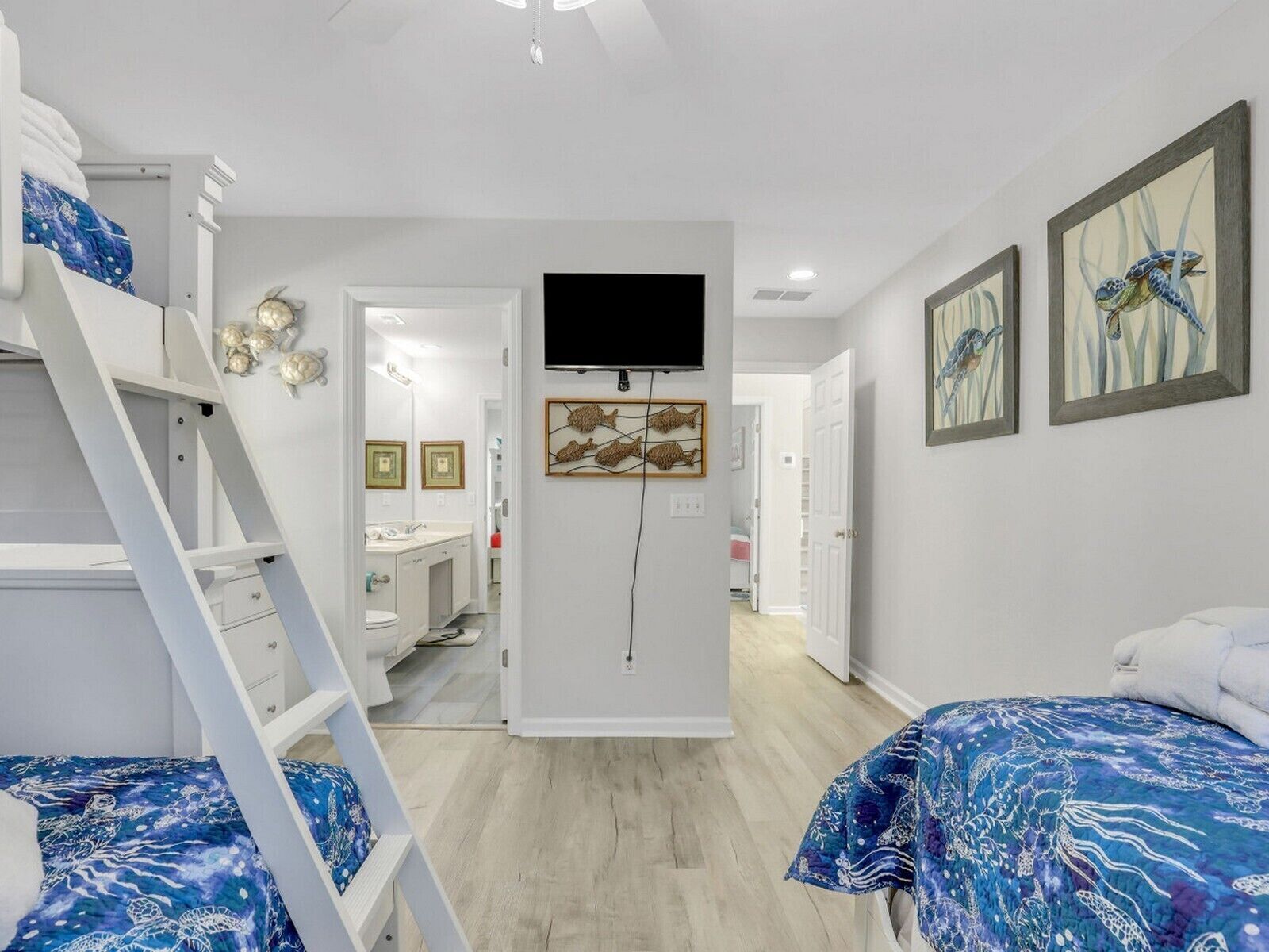 Een slaapkamer met stapelbedden, een televisie, kunstwerken en een badkamer die door een open deur zichtbaar is.