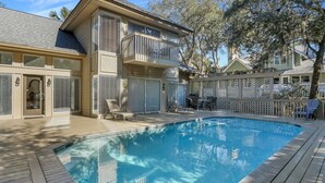 A two-story house with a swimming pool, a covered patio, and a fenced backyard.