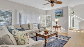 A living room with a sofa, coffee table, and a ceiling fan.
