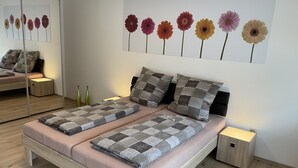A modern bedroom with a bed, two bedside tables, a mirror, and a wall art piece of flowers.