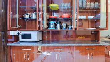 Een koelkast, een magnetron, een kookplaat, kookgerei, borden en bestek