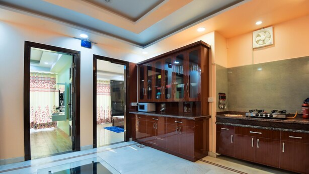 A modern kitchen with dark wooden cabinets, a marble countertop, and a built-in microwave.