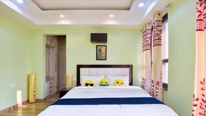 A bedroom with a bed, a headboard, a bedside table, a wall-mounted TV, and a door.