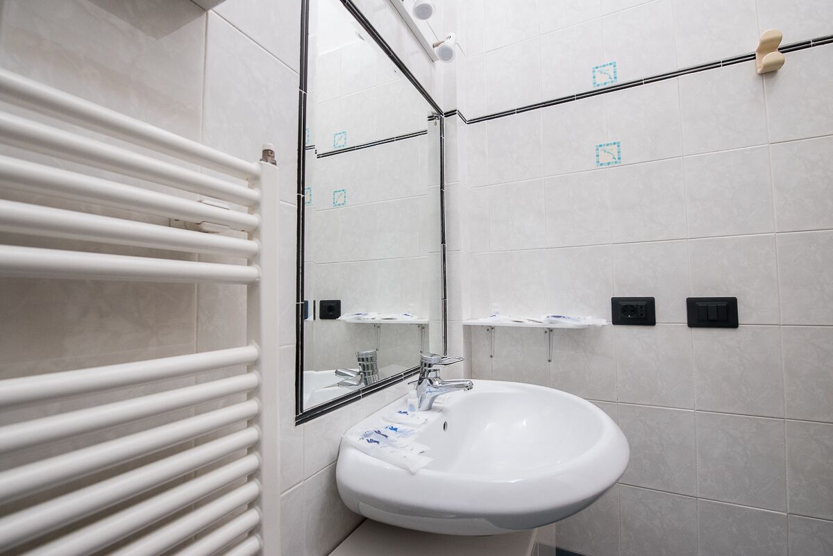 A modern bathroom with a white sink, a mirror, and a towel rack.