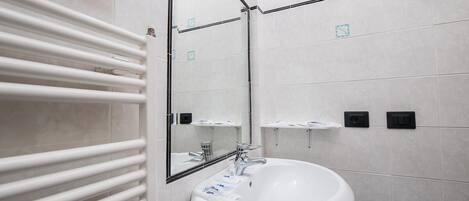 A modern bathroom with a white sink, a mirror, and a towel rack.