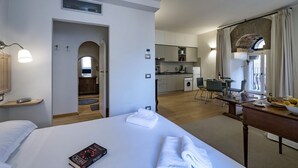 Ein Hotelzimmer mit Bett, Schreibtisch, Esstisch, einer Küche und einem Rundbogenportal.