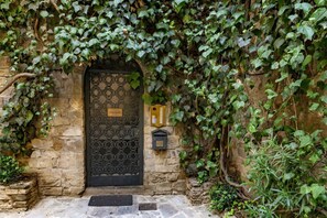 A stone building with a black ornate door, a small plaque, and a wall-mounted light fixture. - Studio apartment in the tower near the Ponte Vecchio (Firenze)