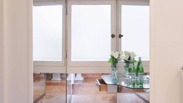 A room with a glass table, white flowers, and green bottles.
