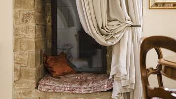 A window with a cushion and a pillow, curtains, and a chair.