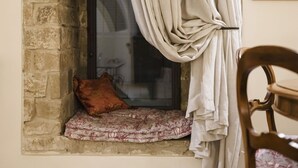 A window with a cushion and a pillow, curtains, and a chair.