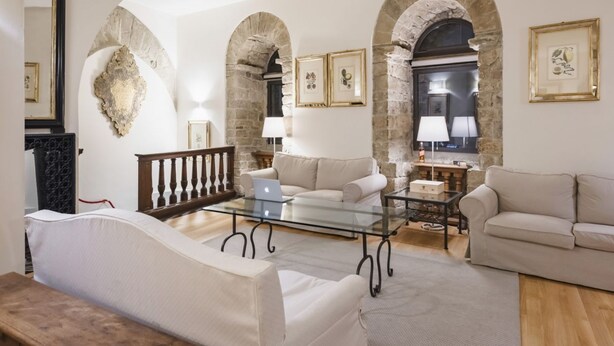 A living room with a glass coffee table, two sofas, and stone arches.
