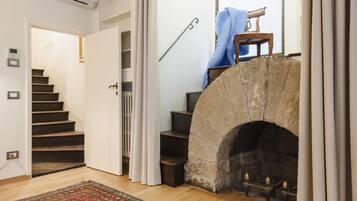 A staircase leading to a second floor, a stone fireplace with a mantel, and a wooden floor.