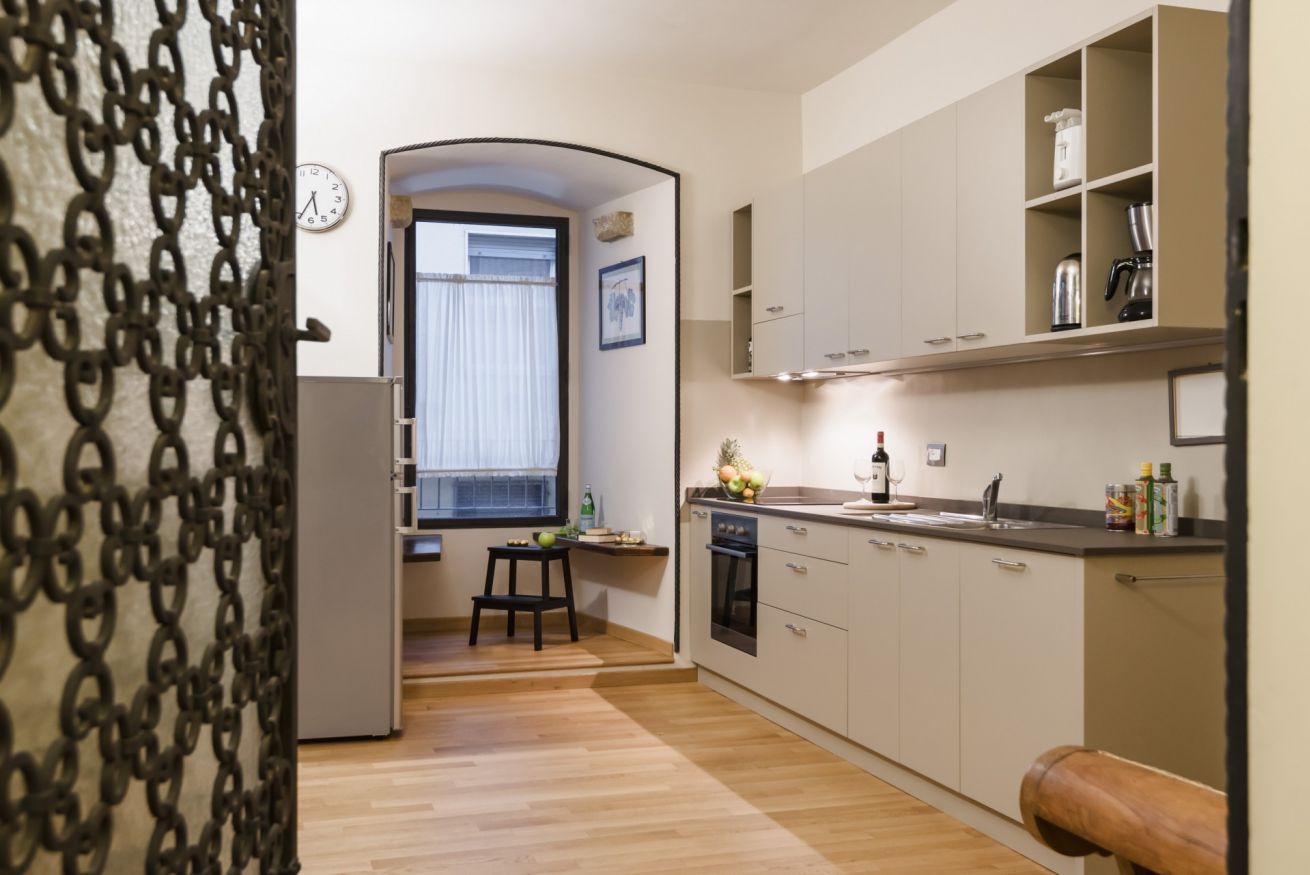 A compact kitchen with wooden flooring, a built-in oven, and a window with a view.