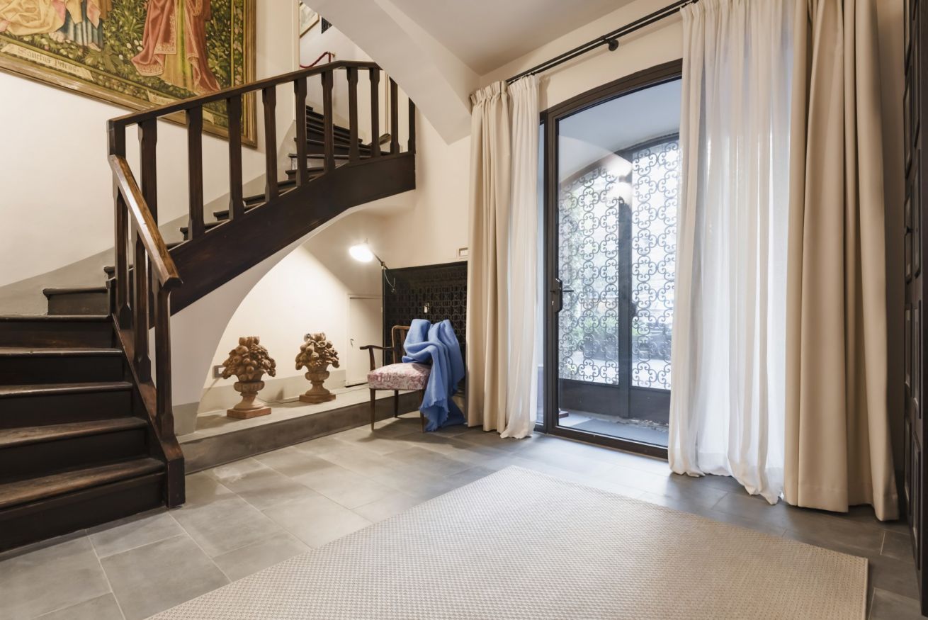 Una scala che conduce a un balcone con vista, una sedia con una coperta e un muro decorativo.
